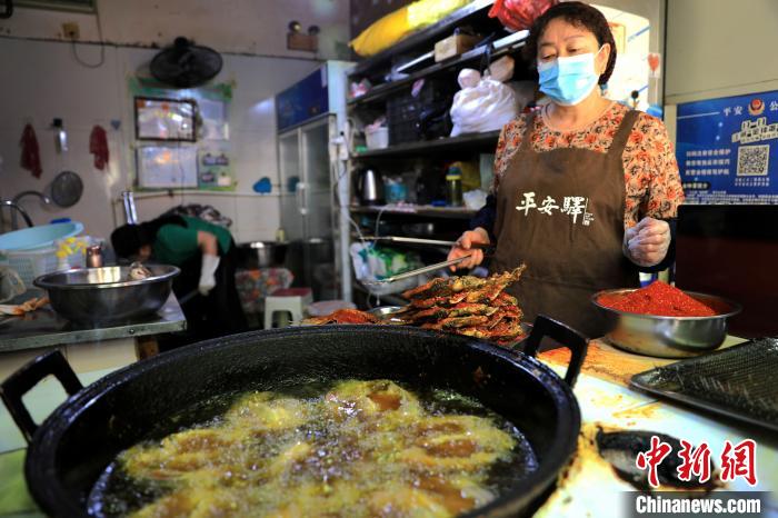 圖為平安驛·河湟民俗文化體驗地內(nèi)的商戶炸干板魚?！⊙Φ?攝